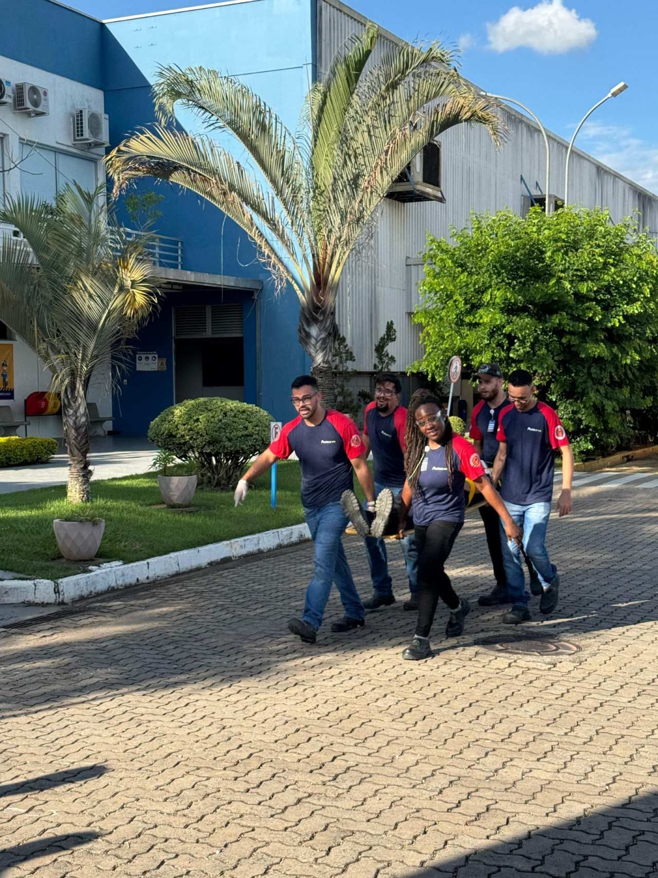 Um grupo de pessoas está caminhando por uma estrada de tijolos em frente a um prédio.