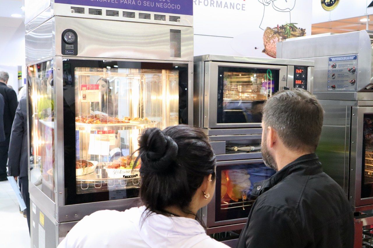 Um homem e uma mulher estão olhando para uma máquina em uma cozinha.