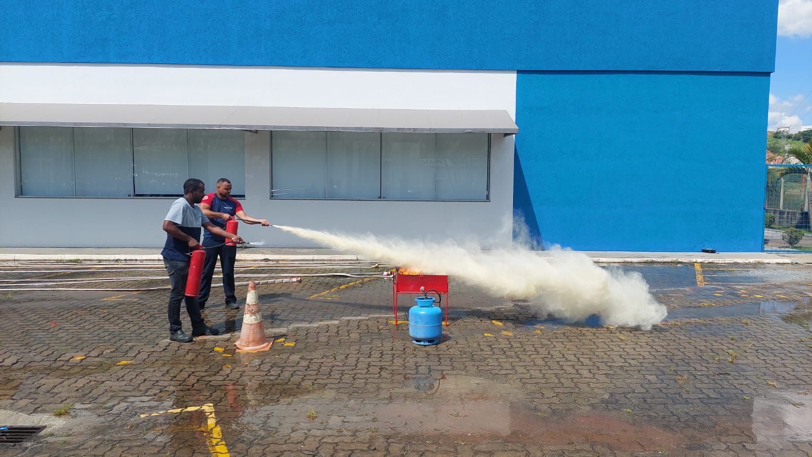 Dois homens estão usando um extintor de incêndio para apagar um incêndio.