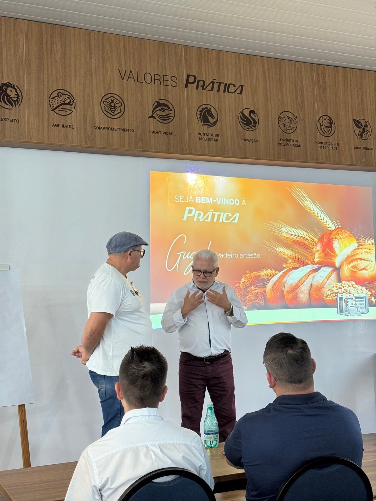 Um grupo de homens está sentado em frente a uma tela de projetor.