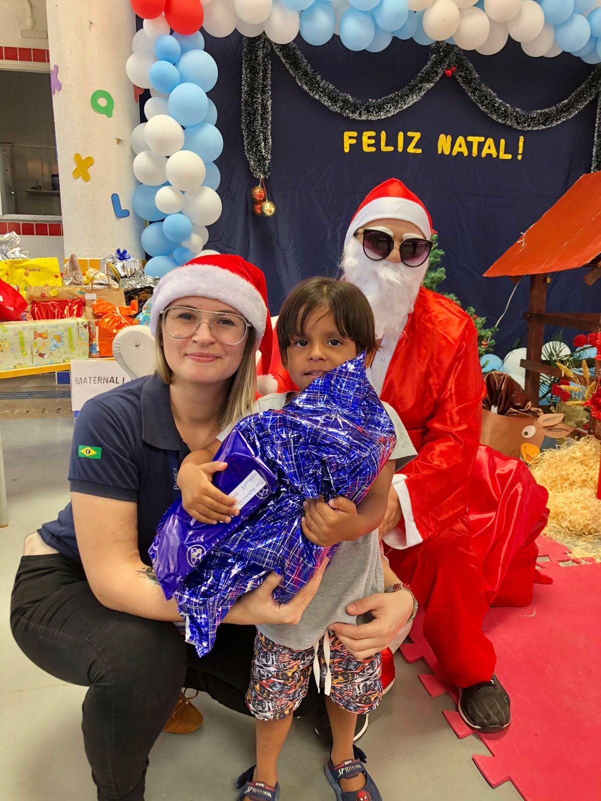 Uma mulher e uma criança estão posando para uma foto com o papai noel.