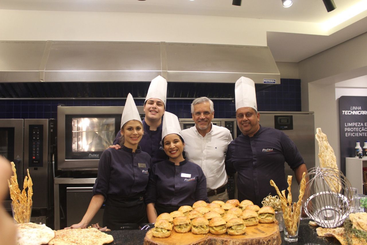 Um grupo de chefs posa para uma foto em uma cozinha