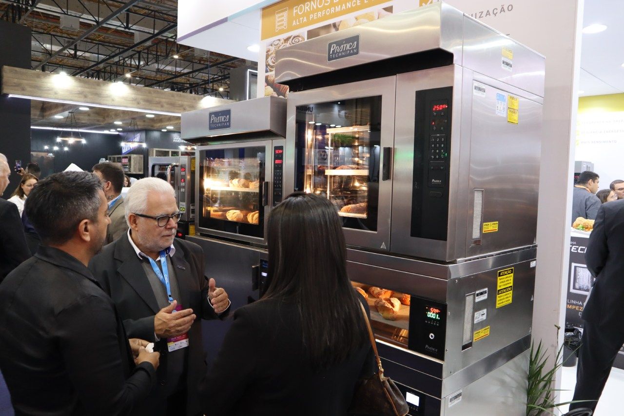 Um grupo de pessoas está em volta de um forno de aço inoxidável.