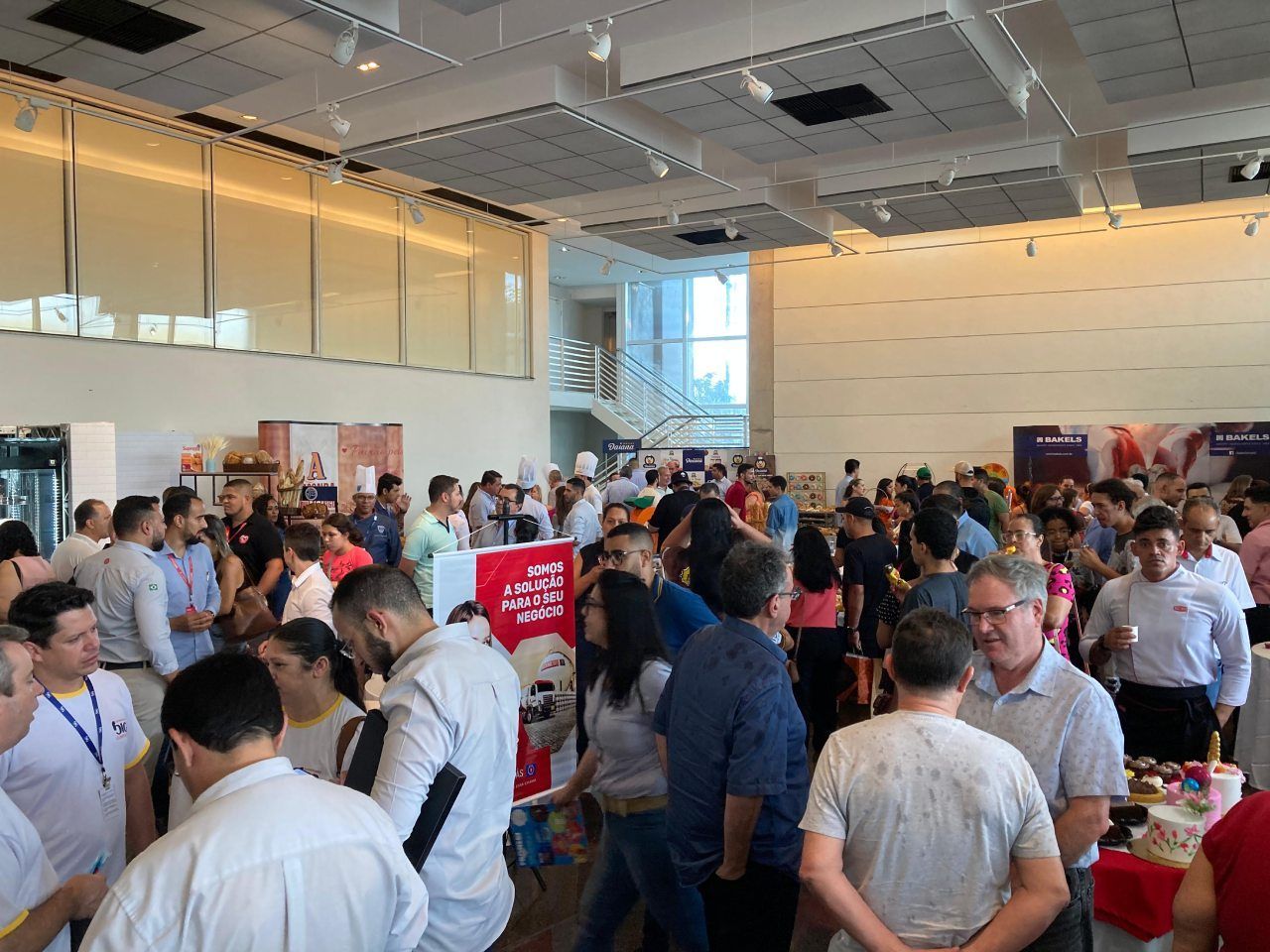 Um grande grupo de pessoas está em uma grande sala.