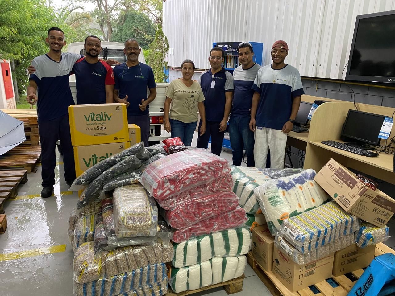 Um grupo de pessoas está posando para uma foto em frente a uma pilha de comida.