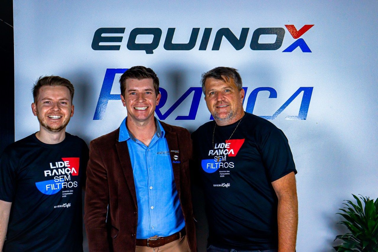 Três homens estão posando para uma foto em frente a uma placa que diz equinócio