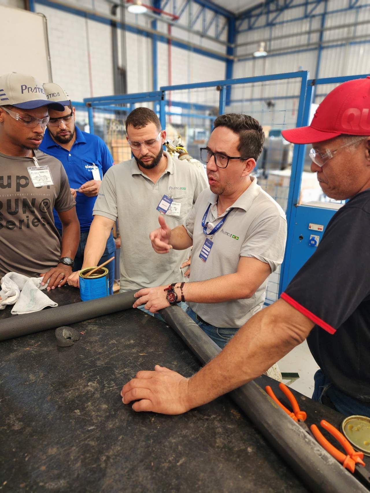 Um grupo de homens está em volta de uma mesa em uma fábrica.