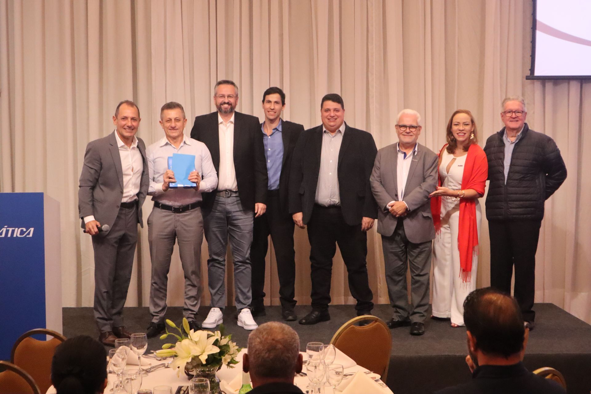 Um grupo de pessoas está de pé, uma ao lado da outra, em um palco.