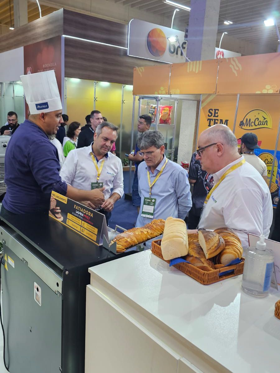 Um homem com chapéu de chef está conversando com um grupo de homens