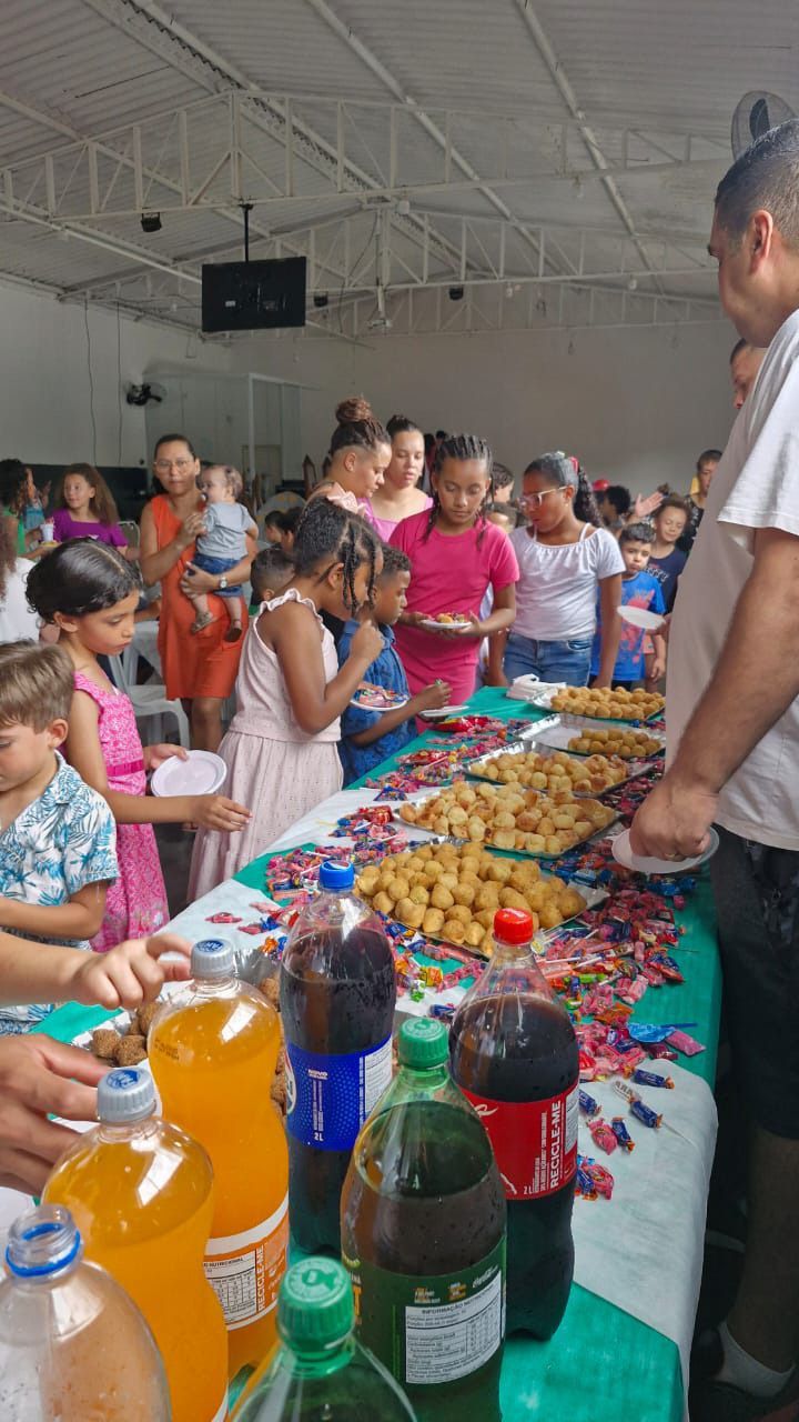 Um grupo de pessoas está em pé ao redor de uma mesa comendo.