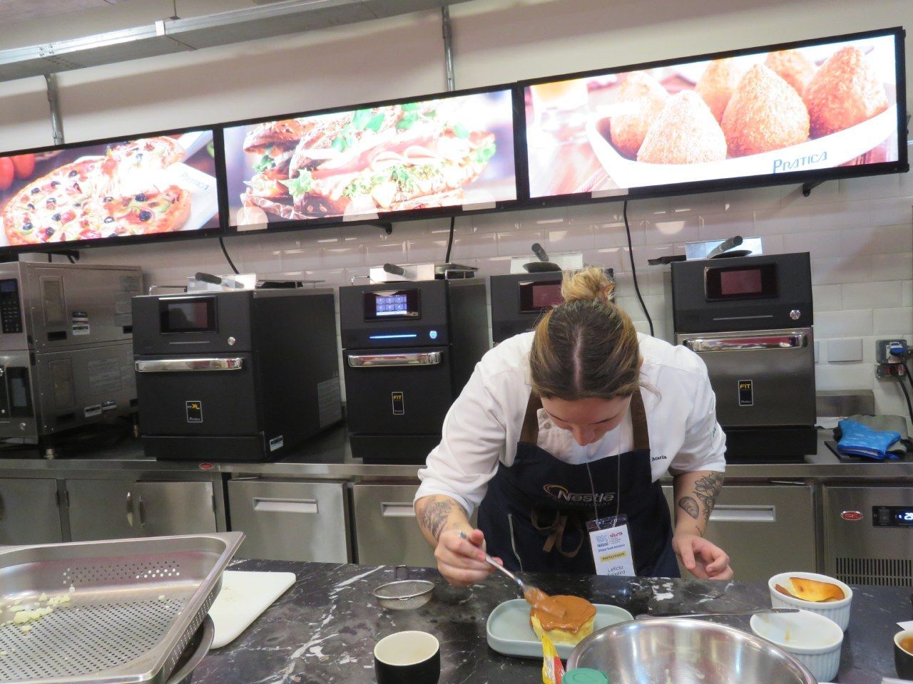Uma mulher está preparando comida em uma cozinha com muitos eletrodomésticos.