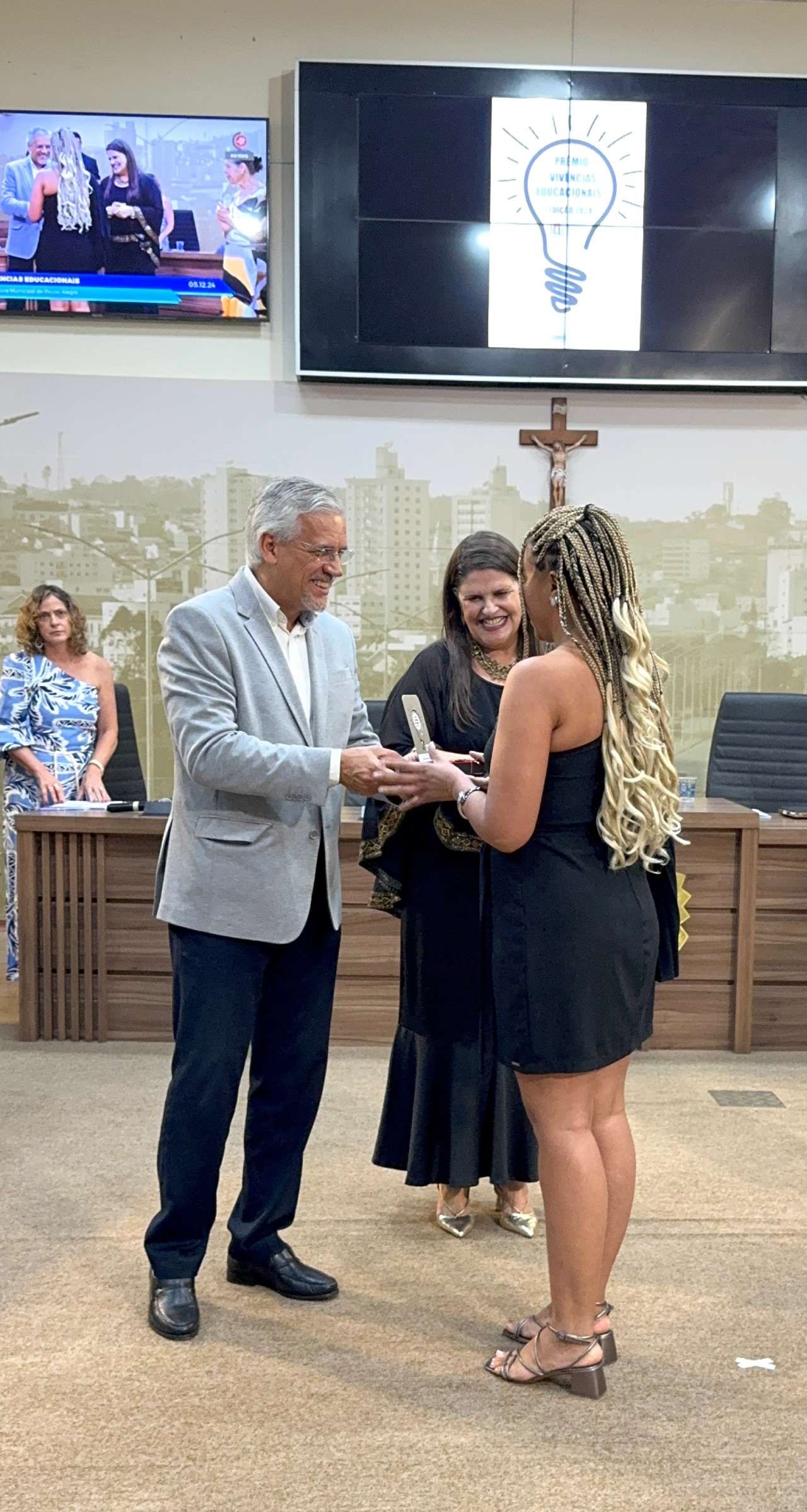 Um homem está dando um troféu a uma mulher em uma sala.