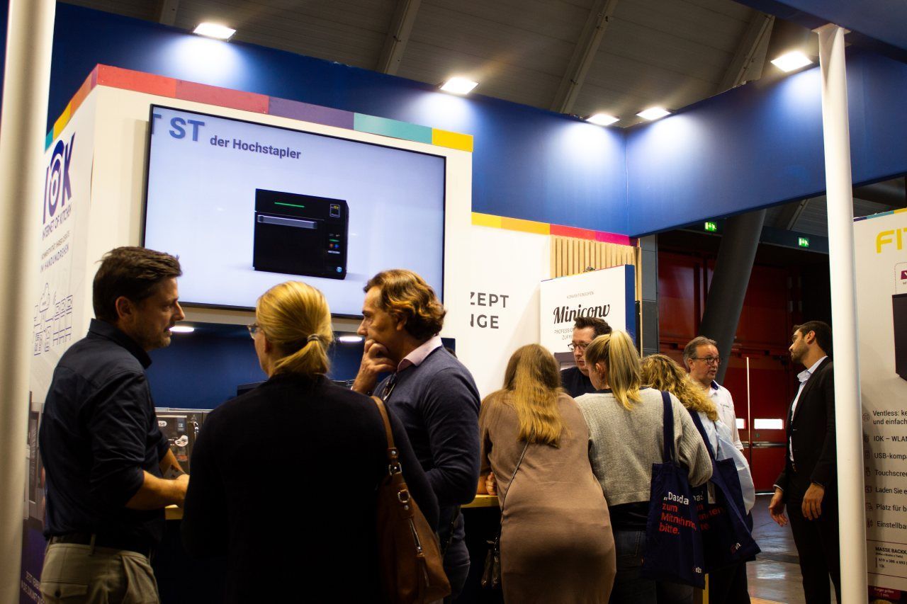 Um grupo de pessoas está em volta de um estande em uma convenção.