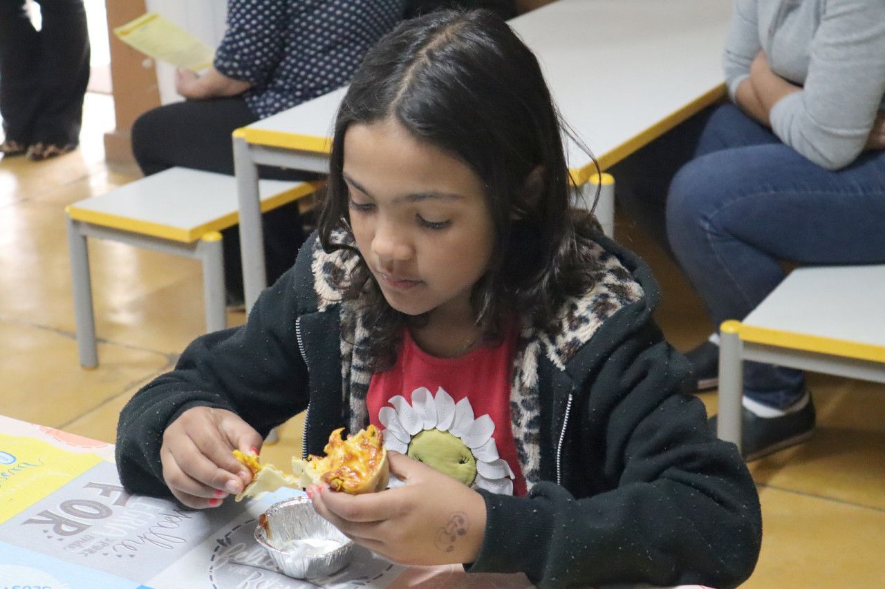 Uma garota está sentada à mesa comendo batatas fritas