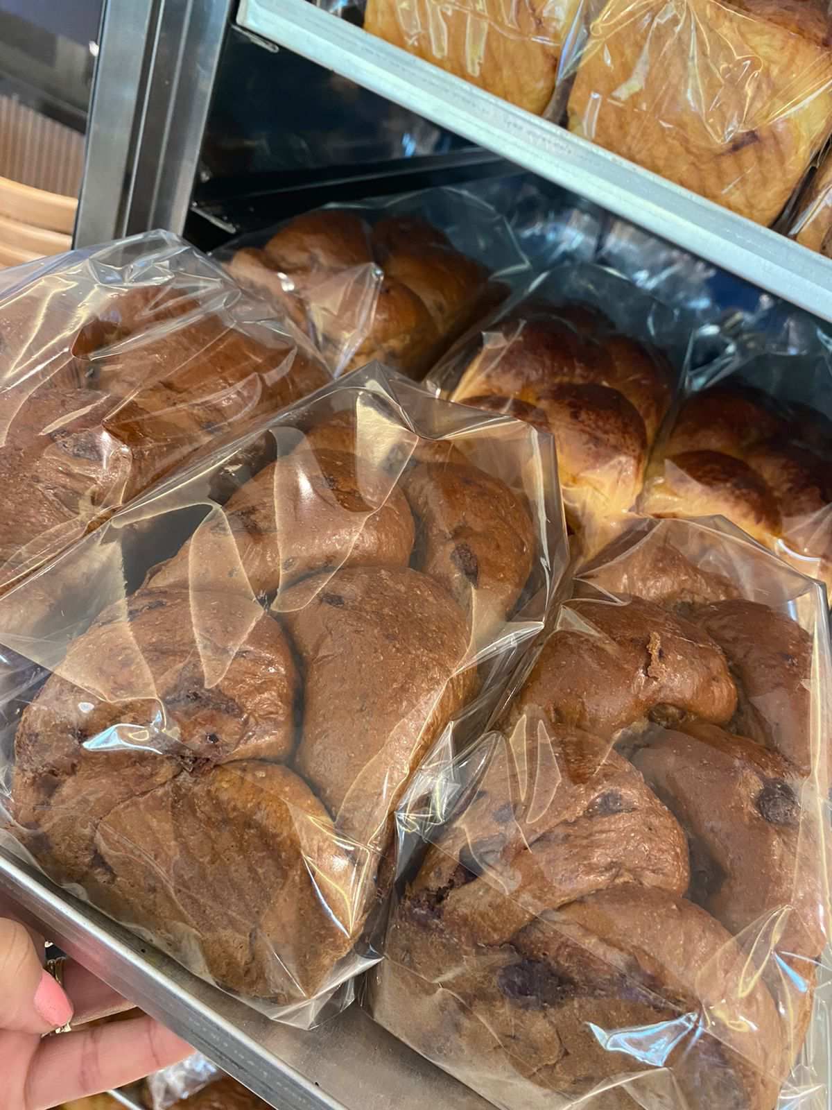 Uma pessoa está segurando uma bandeja de pão em sacos plásticos.