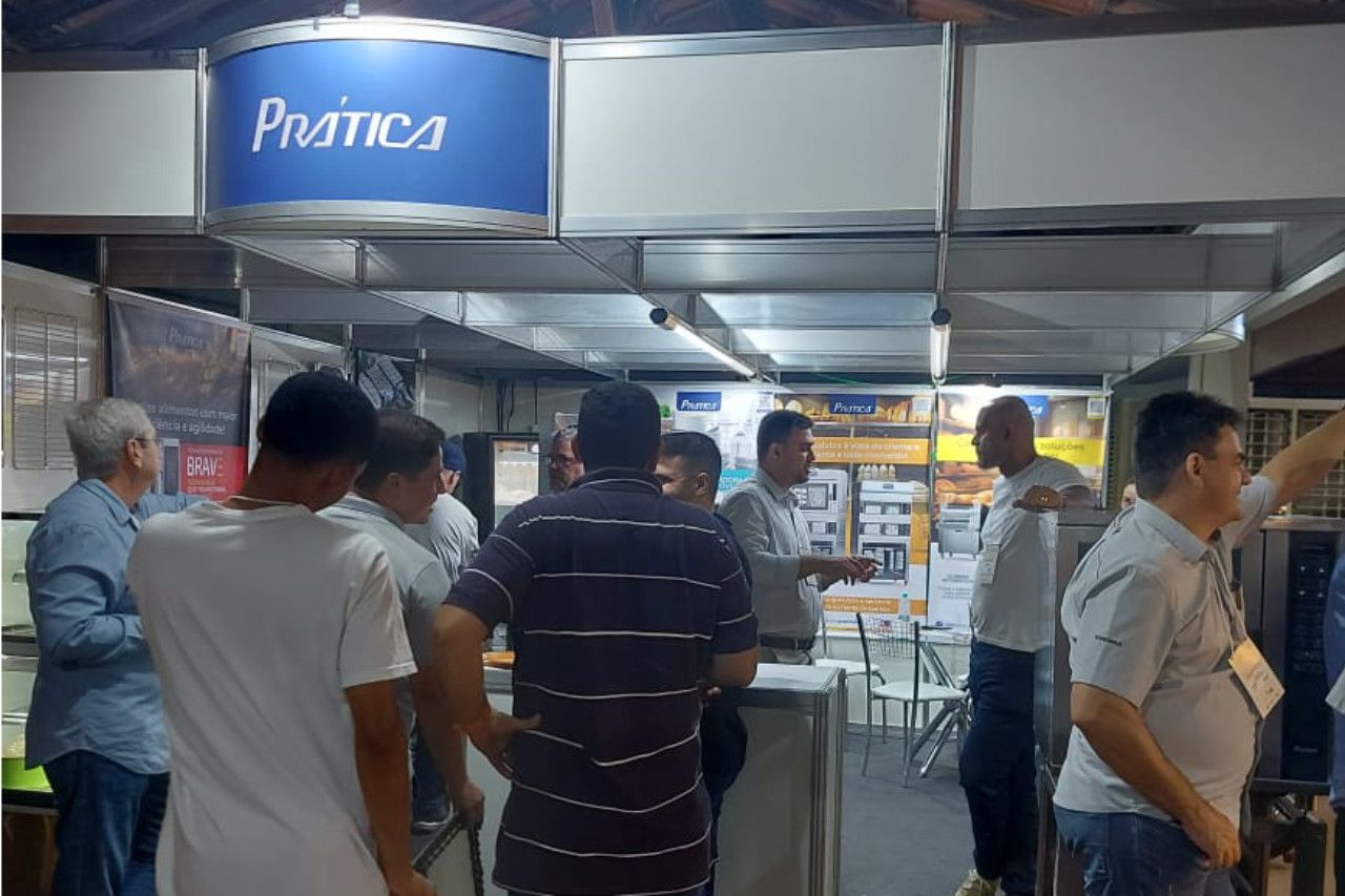 Um grupo de pessoas está em volta de um estande em uma convenção.