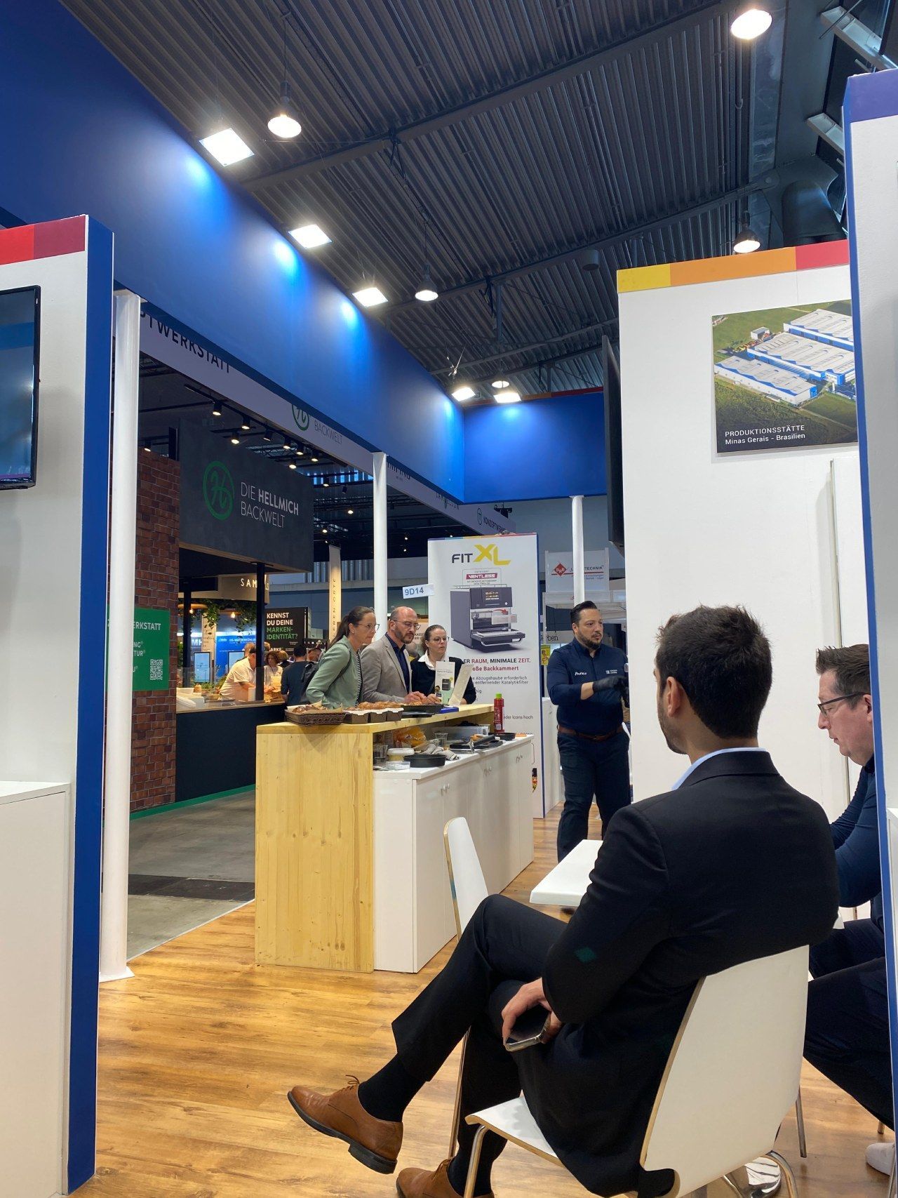 Um homem de terno está sentado em uma cadeira em uma convenção.