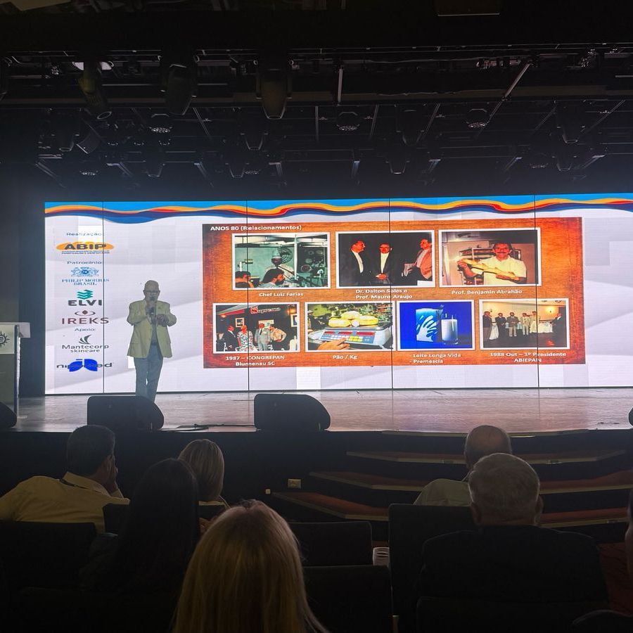 Um homem está fazendo uma apresentação em frente a uma tela grande