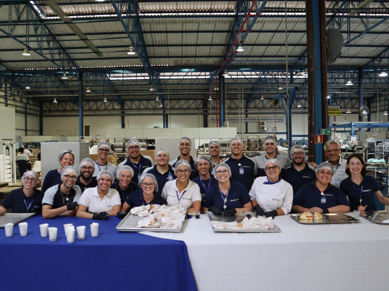 Um grupo de pessoas está posando para uma foto em um armazém.