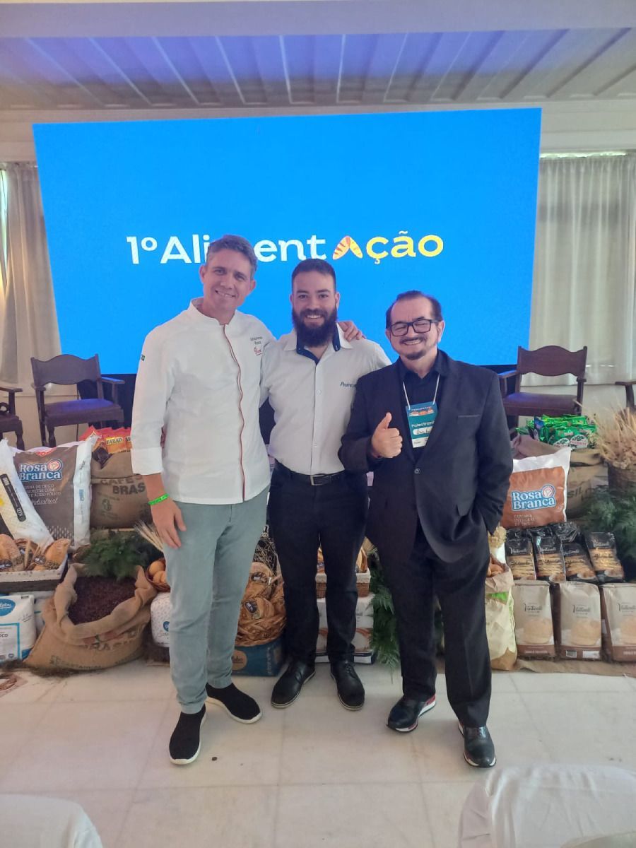 Três homens posam para uma foto em frente a uma tela azul que diz 1o alimentação
