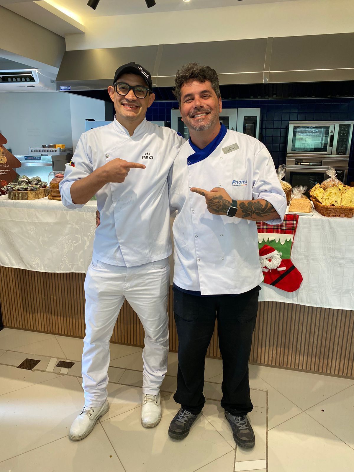 Dois homens estão parados um ao lado do outro em uma cozinha.