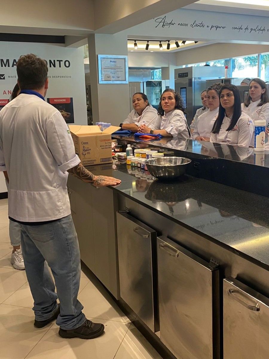 Um grupo de pessoas está em pé ao redor de um balcão na cozinha.