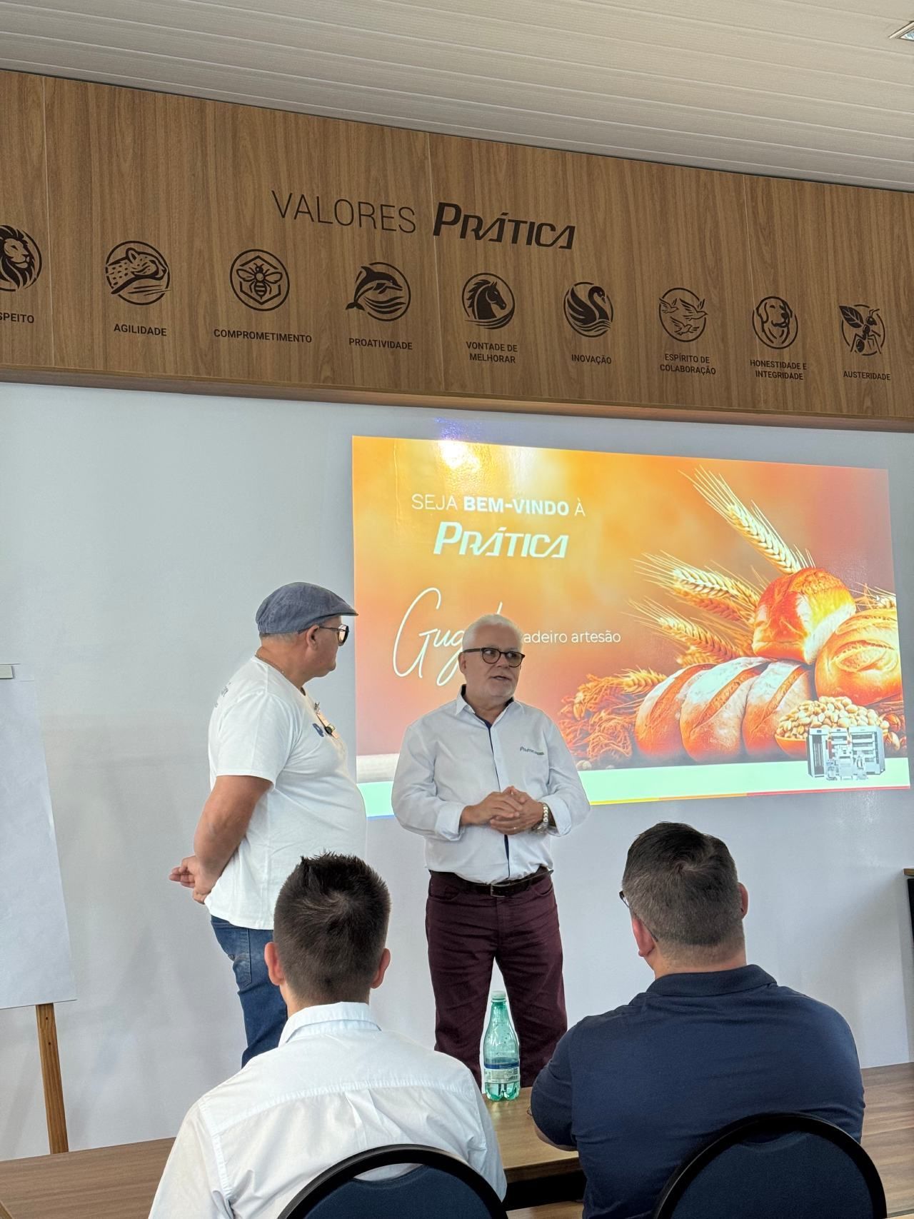 Um grupo de homens está sentado em frente a uma tela de projetor.