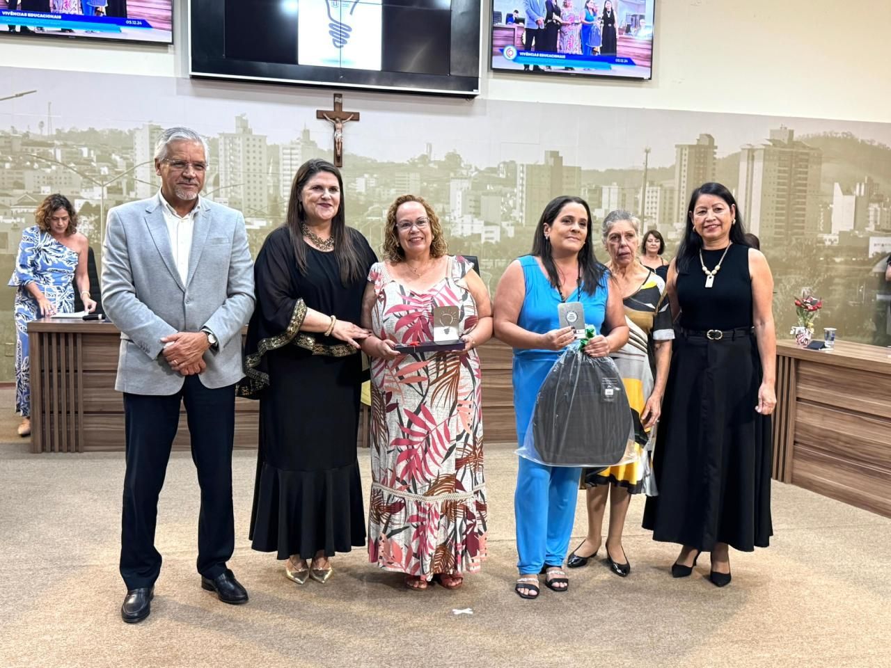 Um grupo de mulheres estão de pé, uma ao lado da outra, em uma sala.