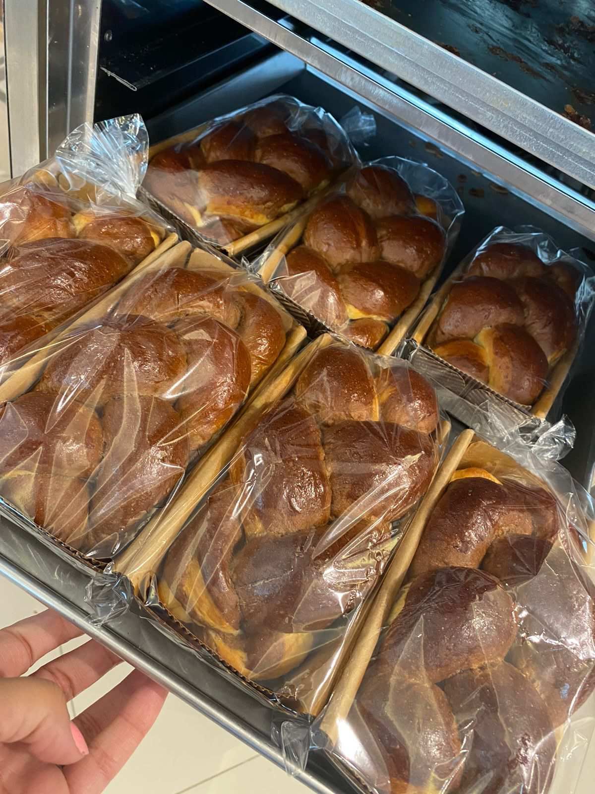 Uma pessoa está segurando uma bandeja de pão em uma padaria.