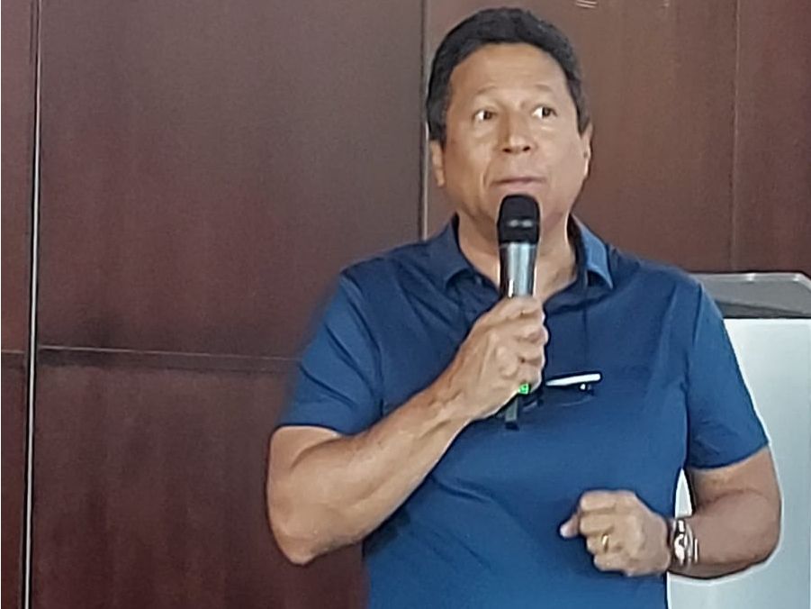 Um homem de camisa azul está segurando um microfone na mão.