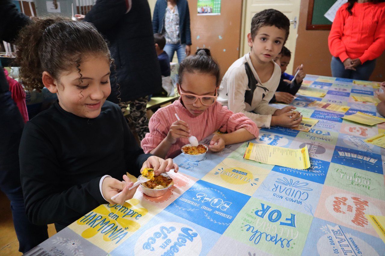 Um grupo de crianças está sentado à mesa comendo.