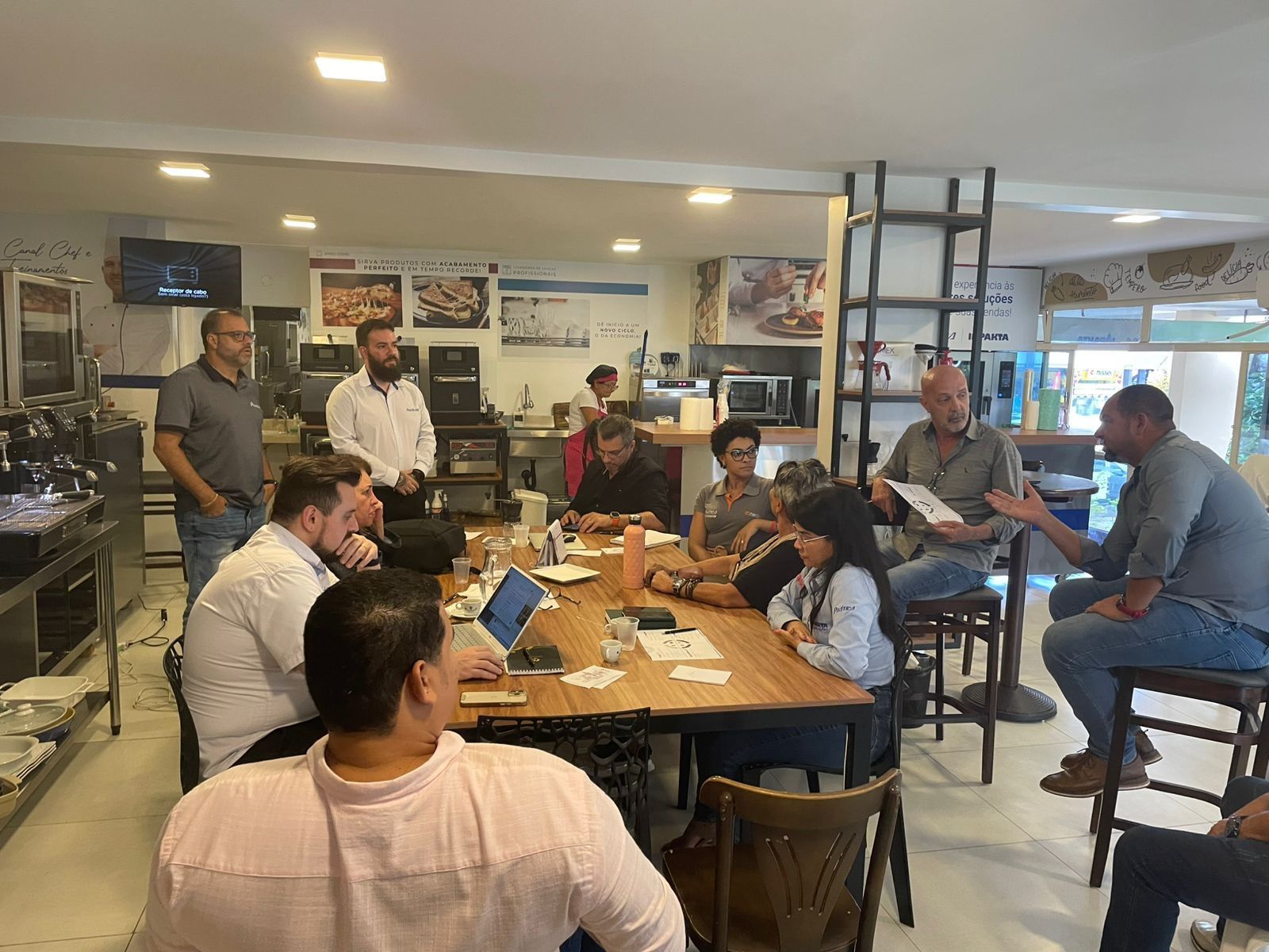 Um grupo de pessoas está sentado ao redor de uma mesa em um restaurante.