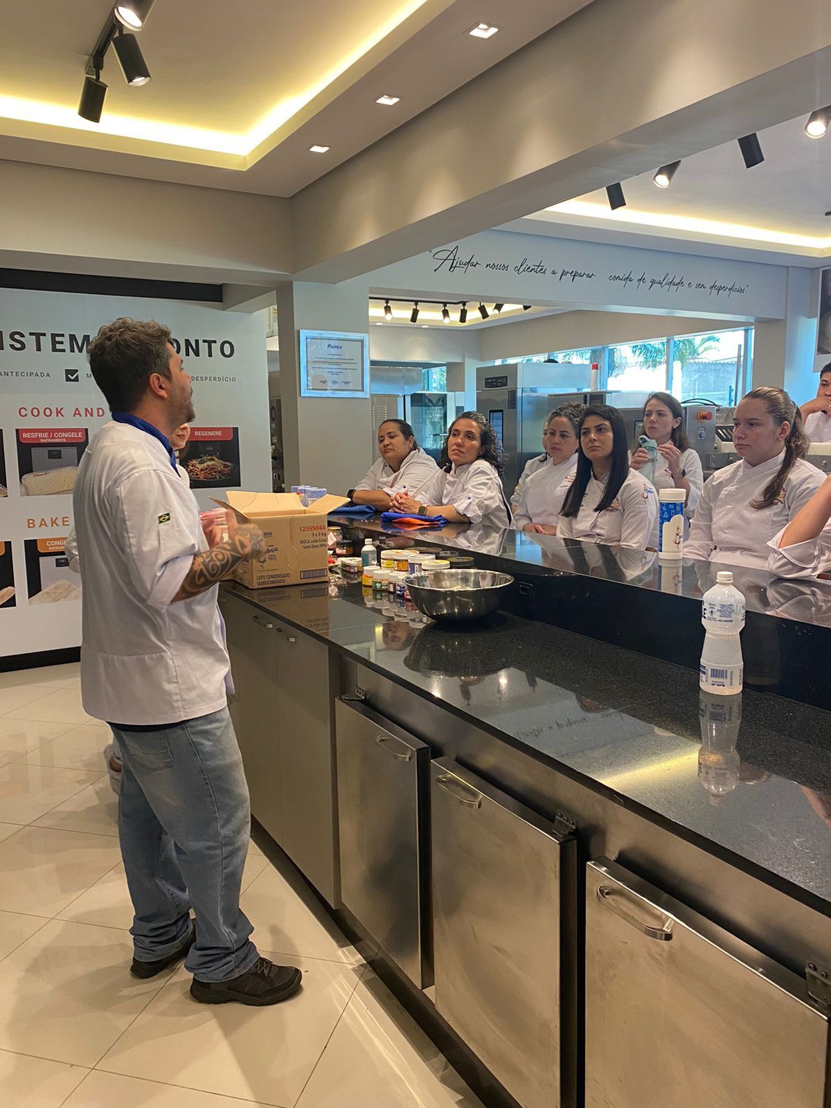Um homem está parado na frente de um grupo de pessoas em uma cozinha.