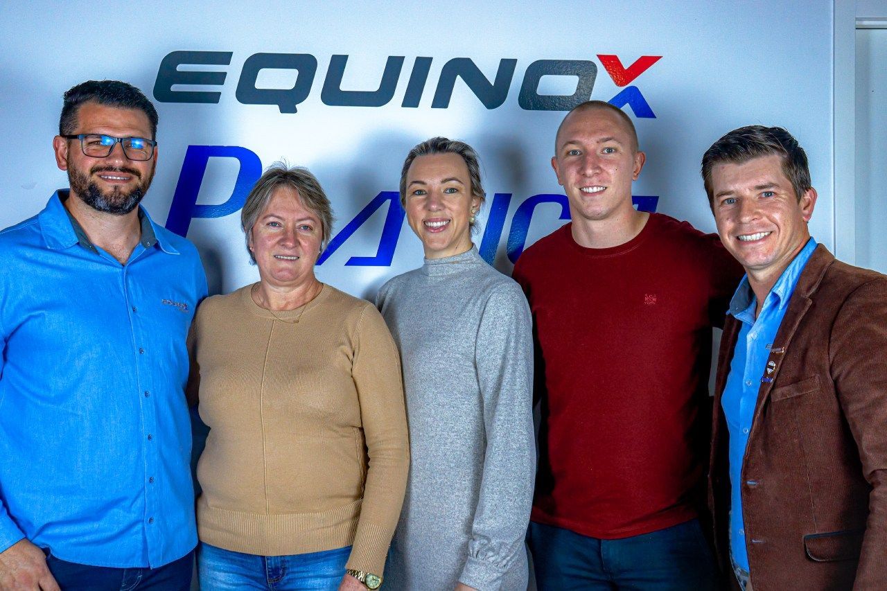 Um grupo de pessoas está posando para uma foto em frente a um sinal de equinócio.