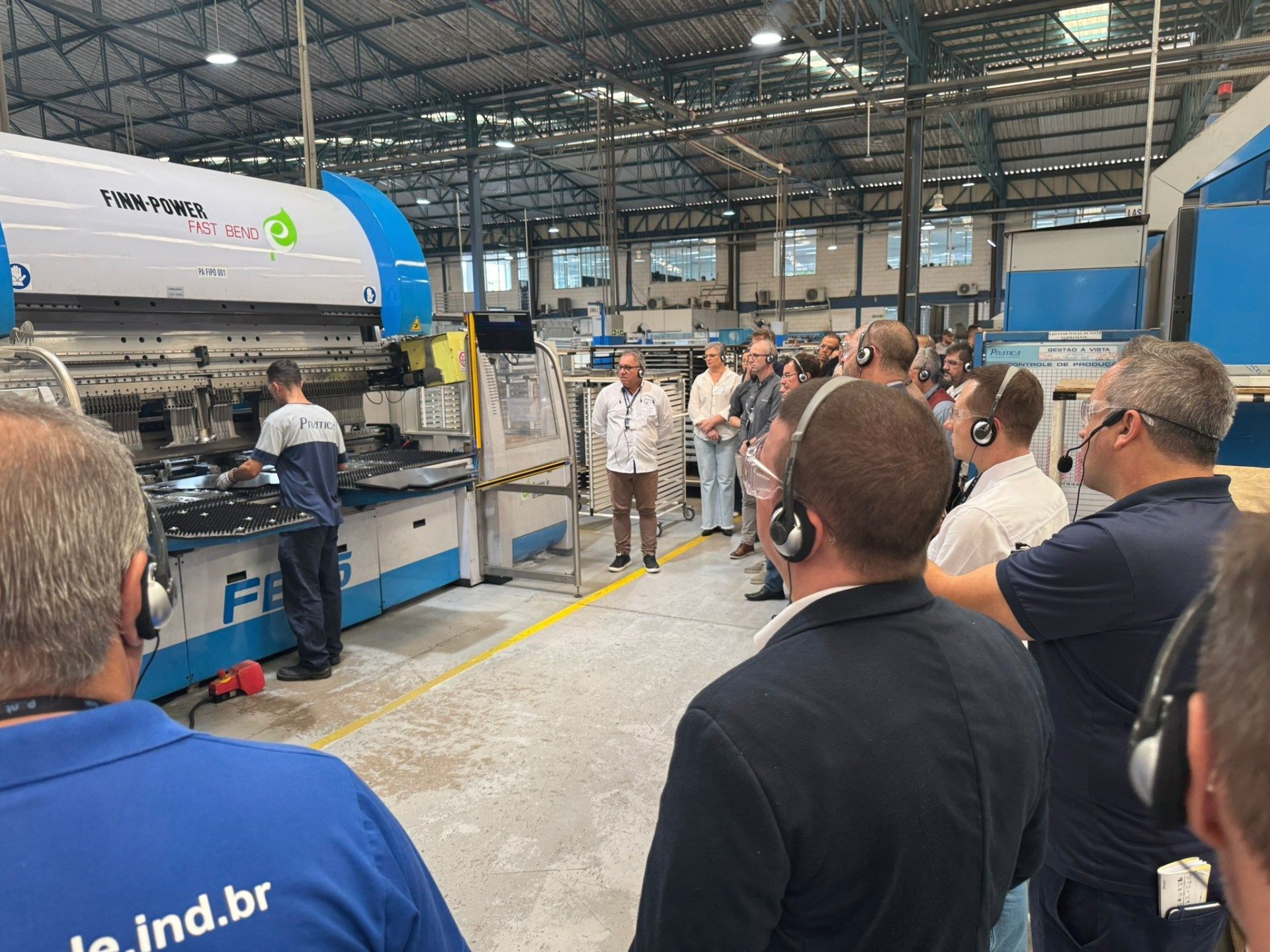 Um grupo de homens está em frente a uma máquina em uma fábrica.