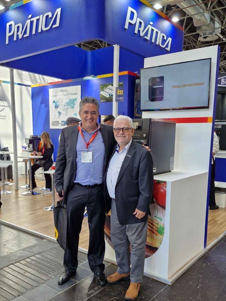 Dois homens estão posando para uma foto em frente a um estande de prática