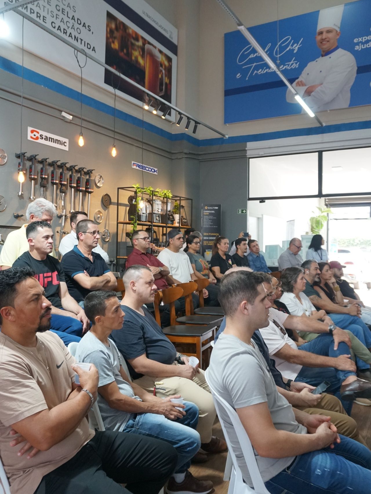 Um grupo de homens em roupas casuais sentados em ambientes fechados, ouvindo.