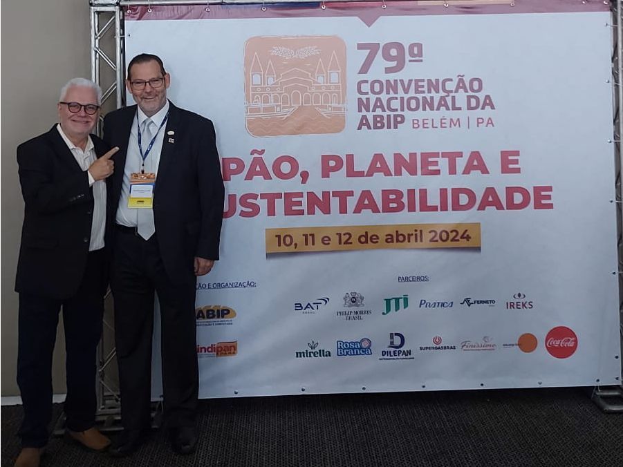 Two men standing in front of a sign that says pão planeta e sustentabilidade