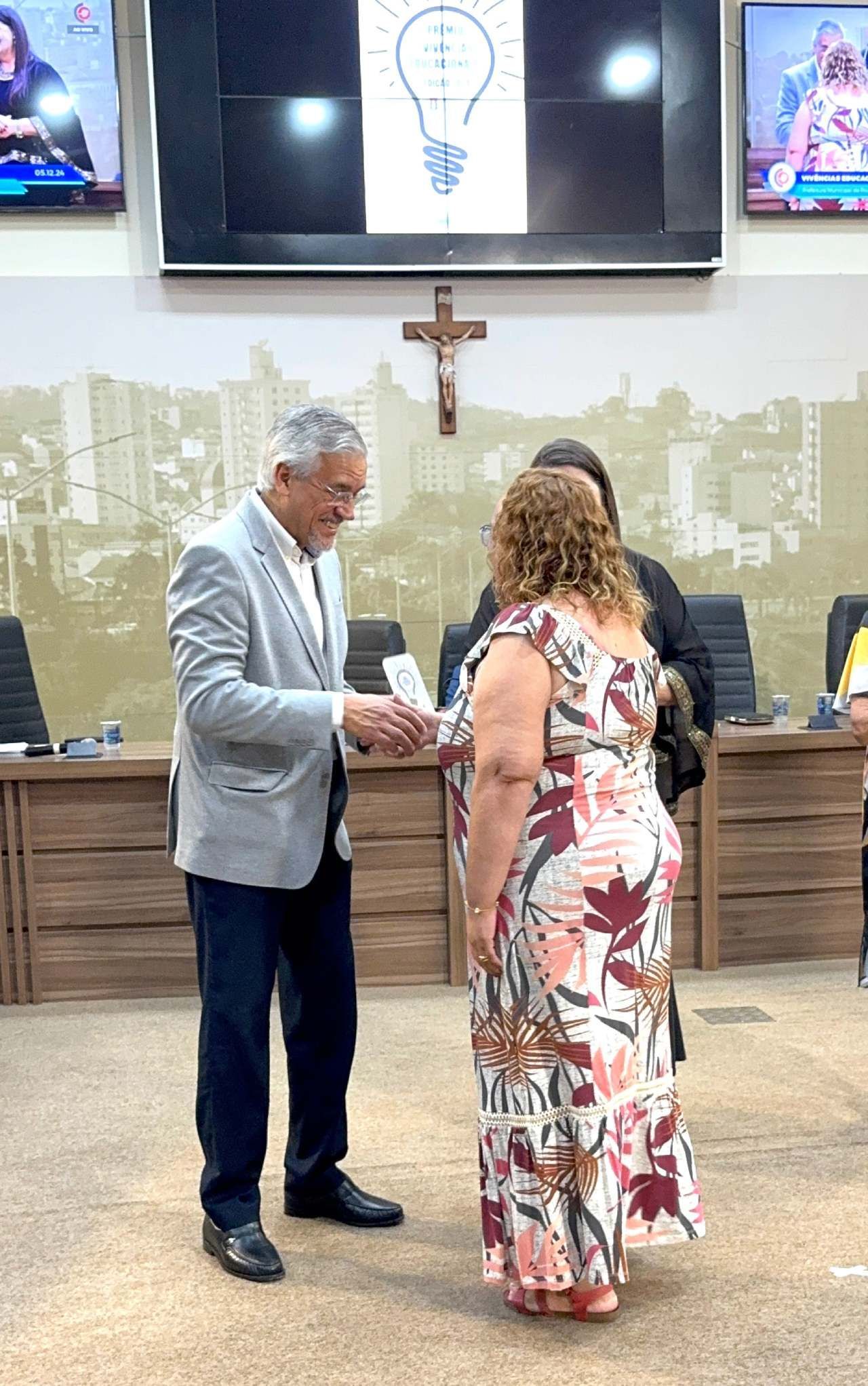 Um homem aperta a mão de uma mulher em uma sala.
