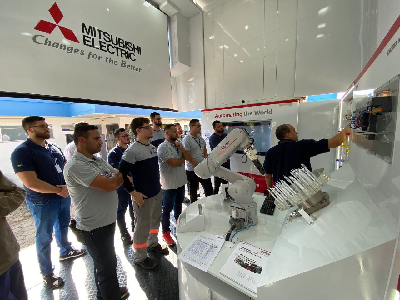 Um grupo de homens está em frente a uma placa da mitsubishi electric.