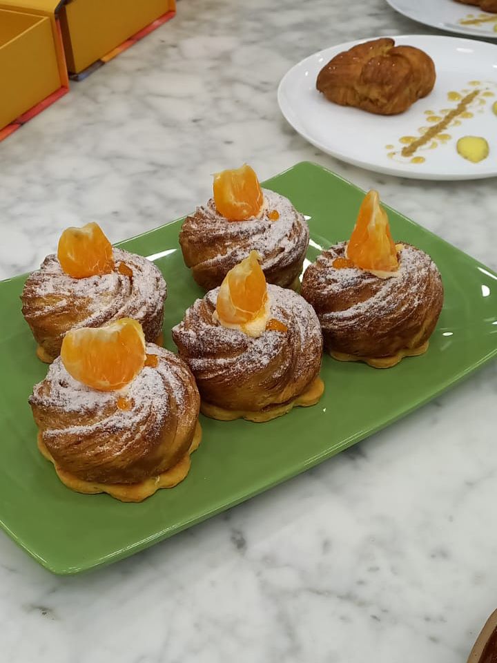 Um prato verde coberto com quatro pastéis com fatias de laranja por cima