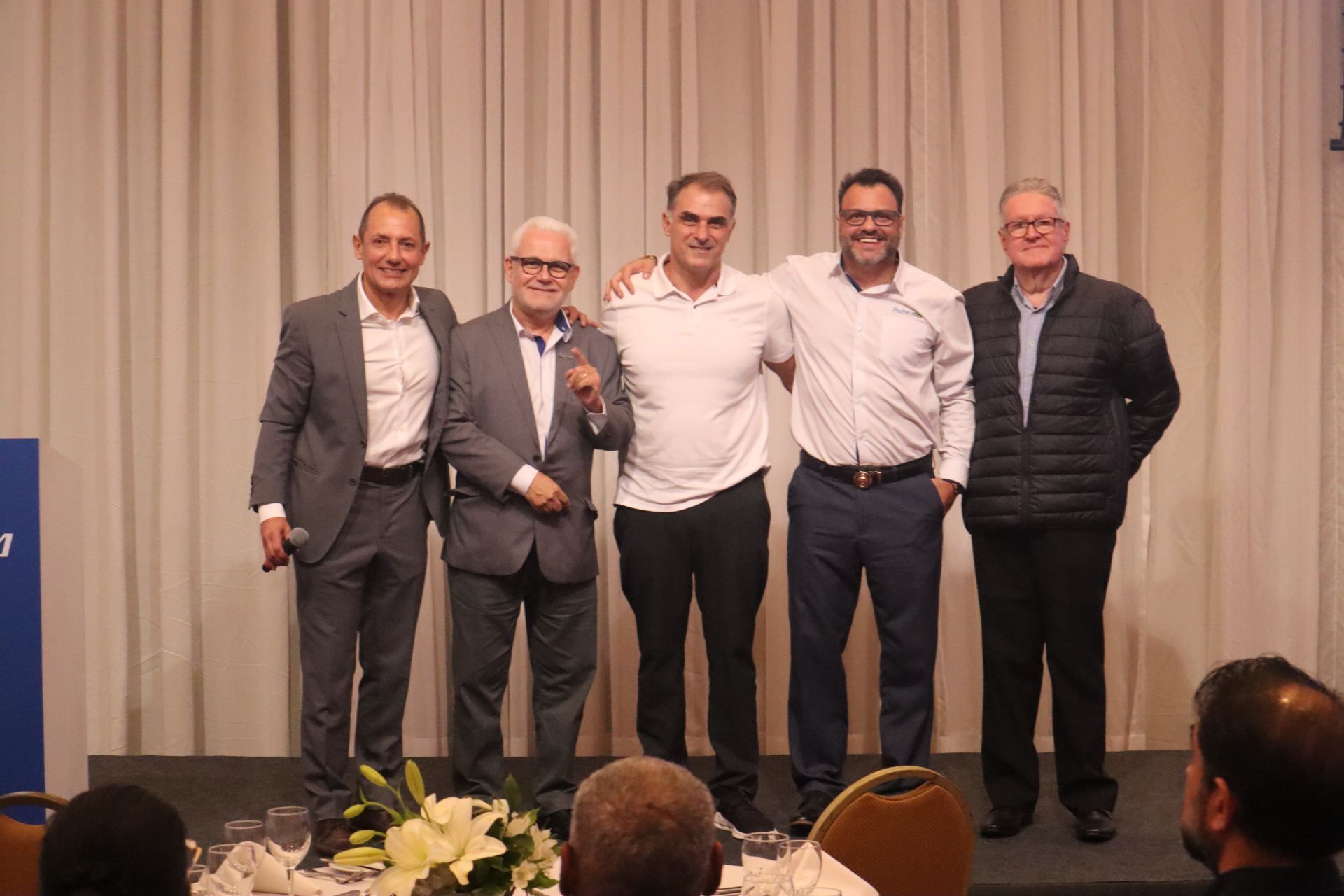 Um grupo de homens estão de pé, um ao lado do outro, em um palco.