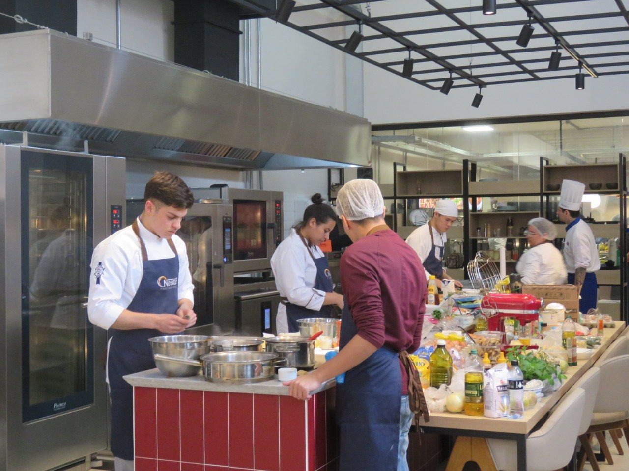 Um grupo de chefs está preparando comida em uma cozinha.