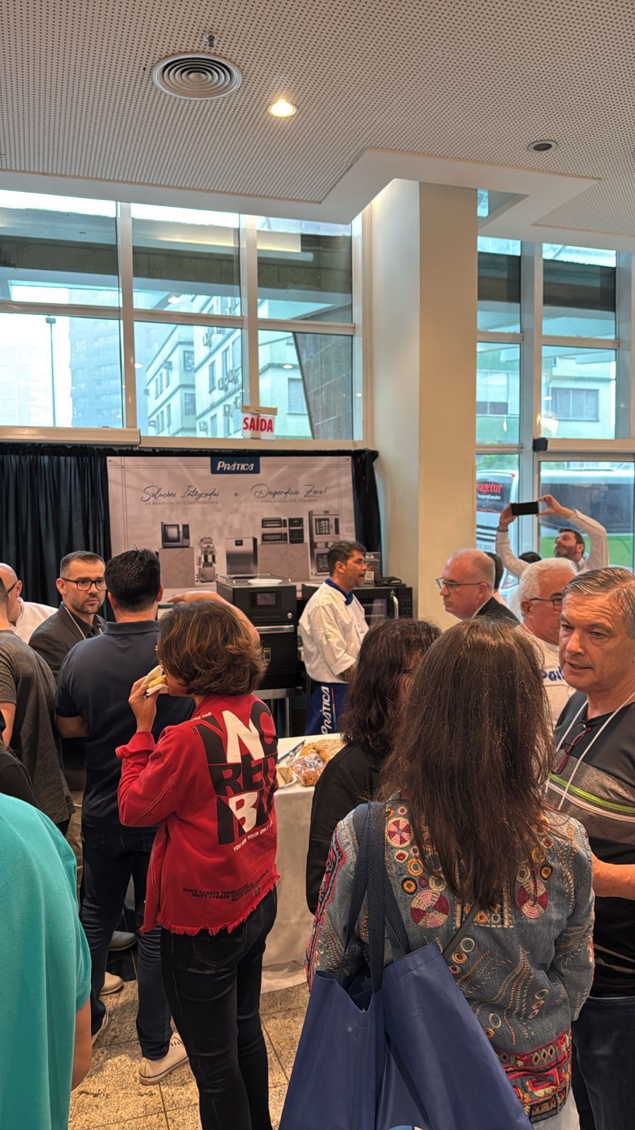 Um grupo de pessoas está em uma sala conversando entre si.