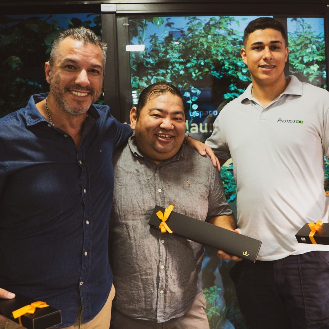 Três homens estão posando para uma foto, um deles vestindo uma camisa que diz 'platina'