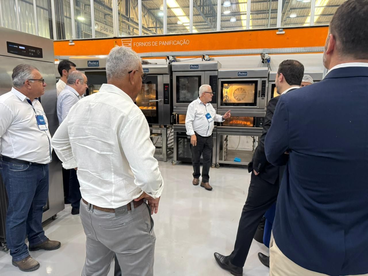Grupo de pessoas participando de uma demonstração de equipamentos de padaria em uma feira comercial.