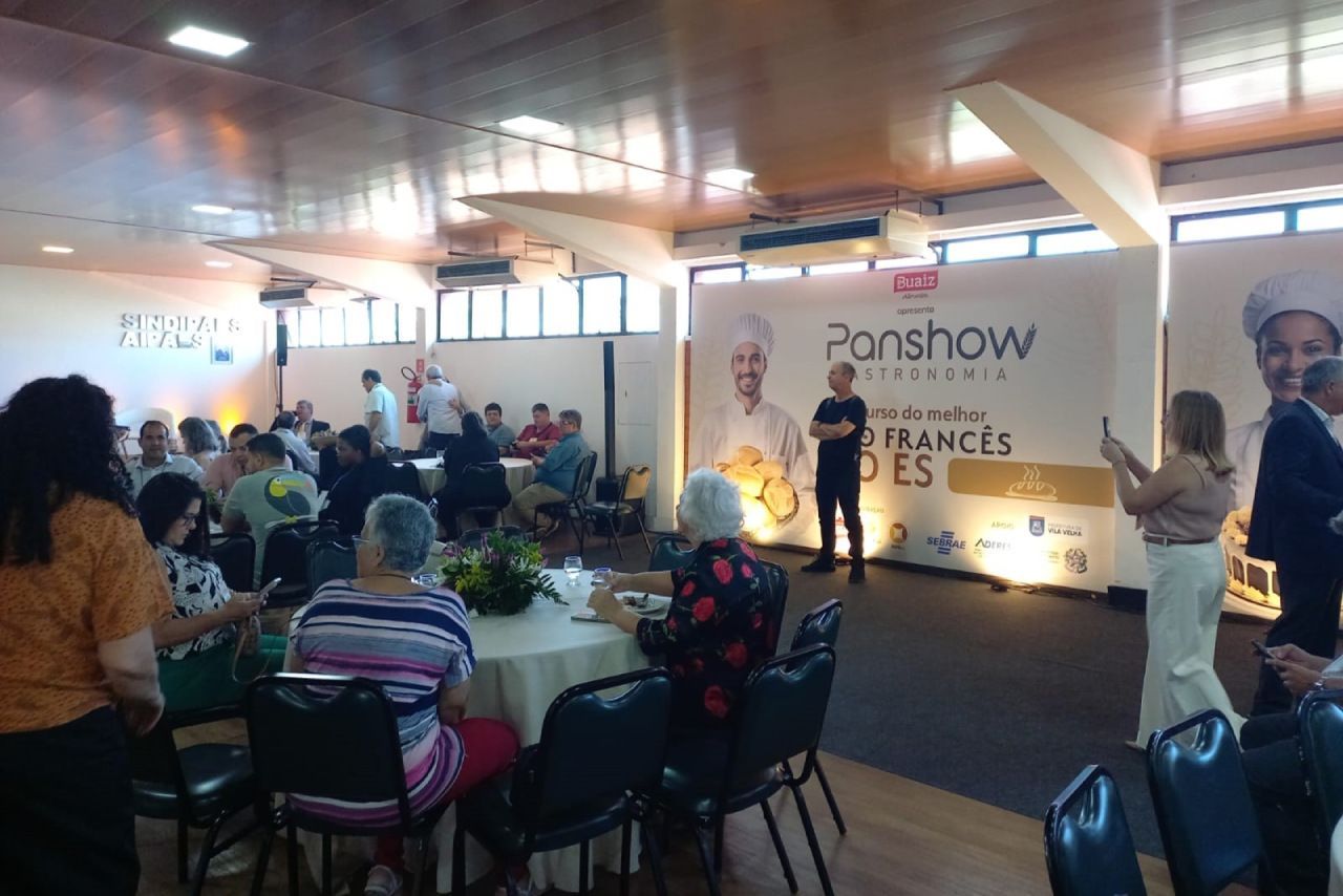 Um grupo de pessoas está sentado em mesas em uma sala.