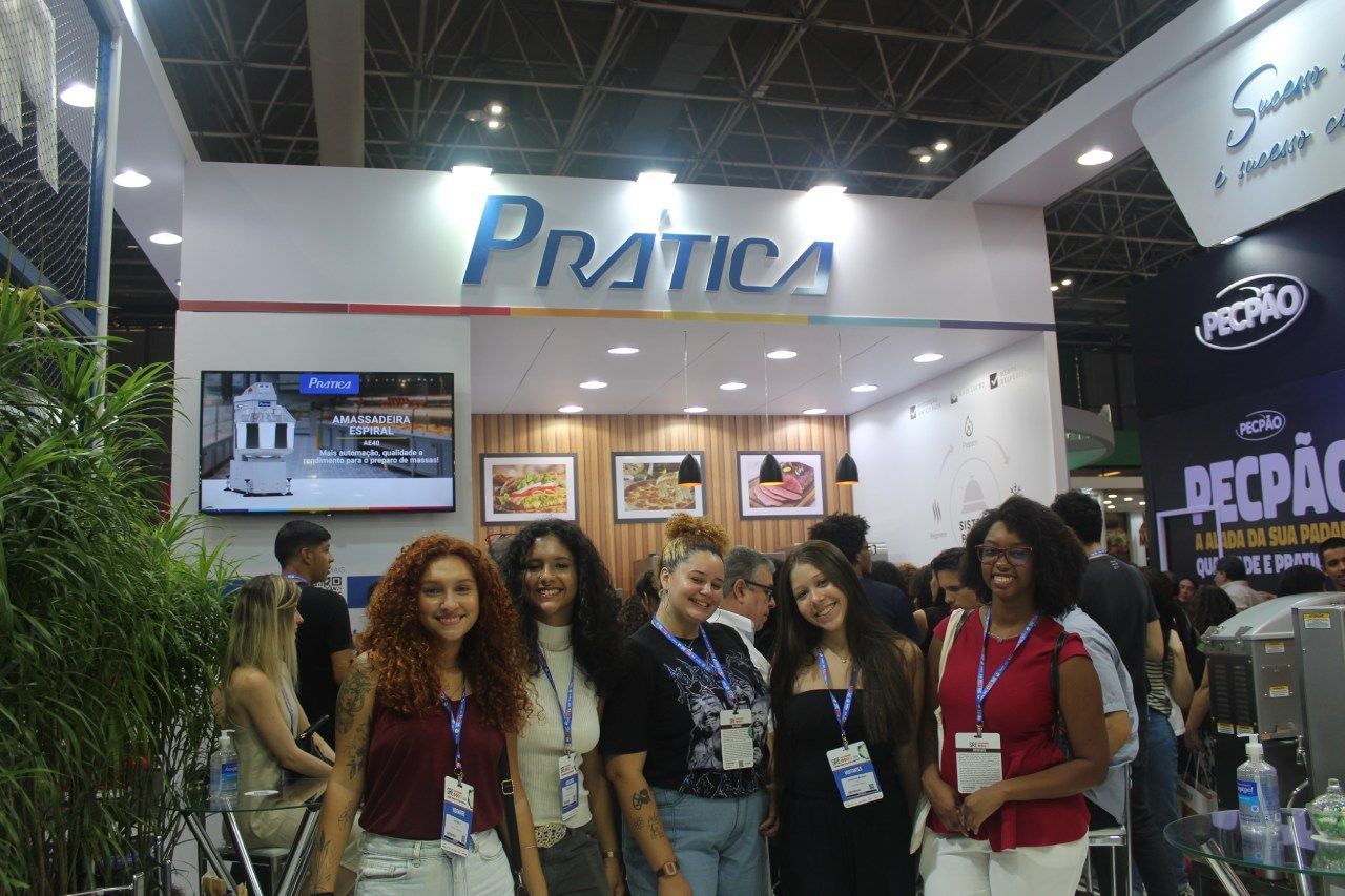 Um grupo de mulheres posa para uma foto em frente a uma cabine de ensaio.
