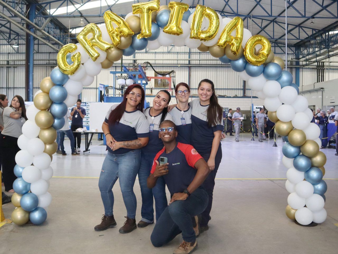 Um grupo de pessoas está posando para uma foto sob um arco de balões.