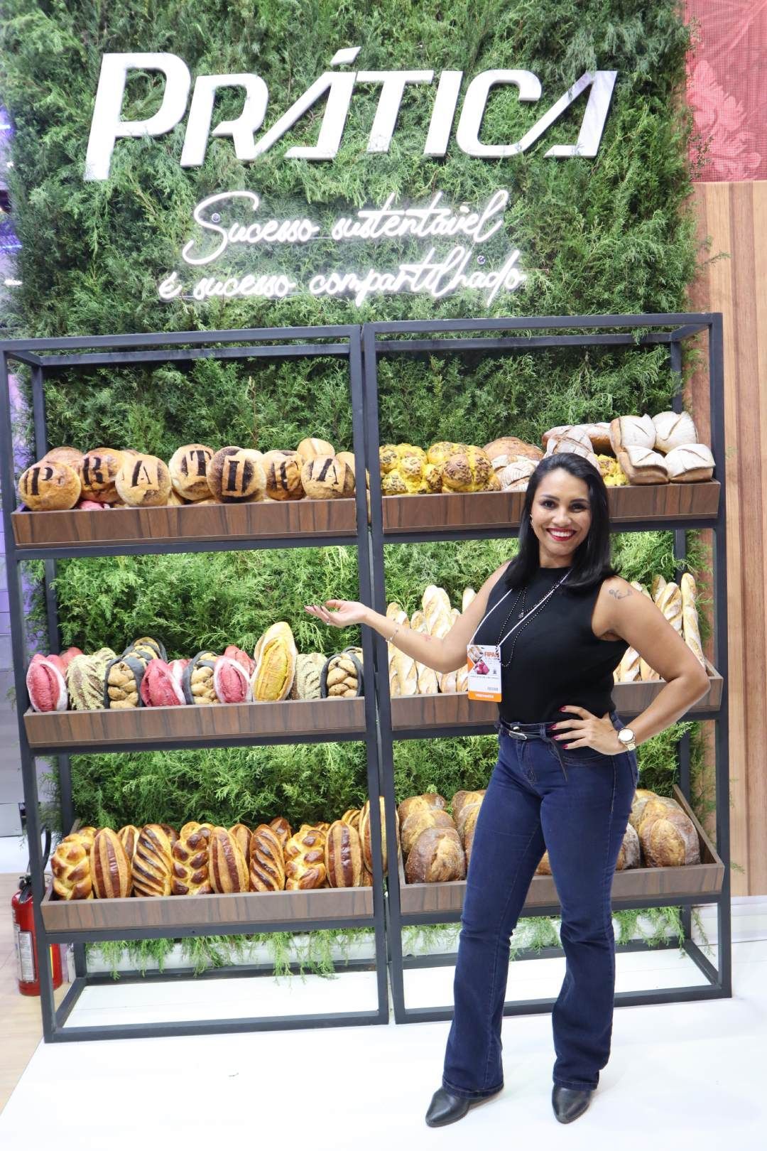 Uma mulher está parada em frente a uma vitrine de pães.